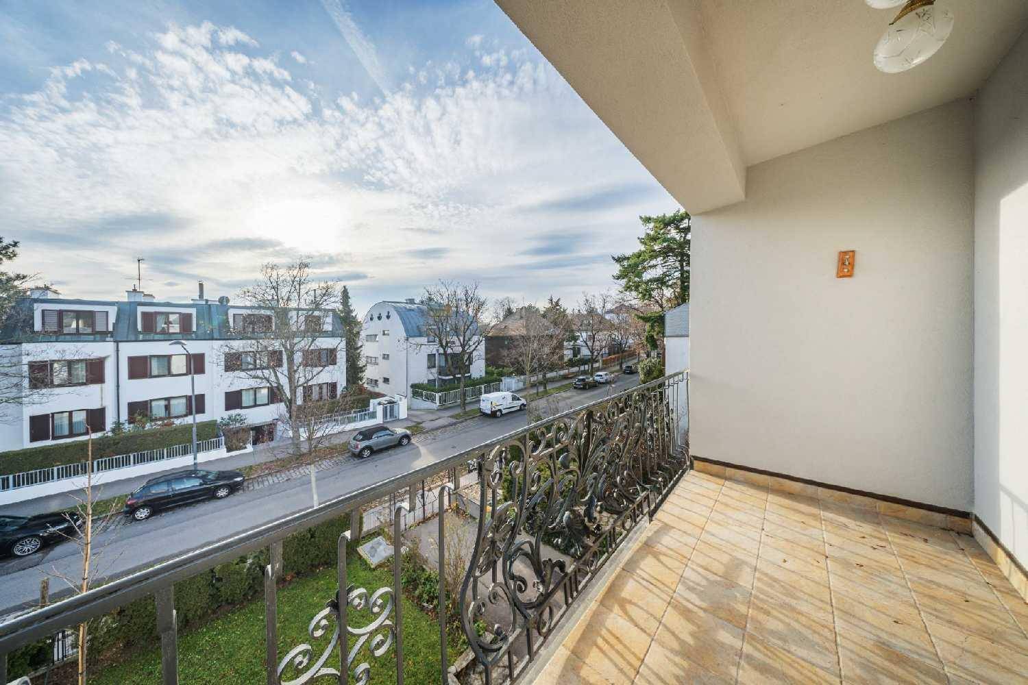 Geräumiger Balkon mit kunstvollem Geländer und weitem Blick auf die Straße und umliegende Häuser.