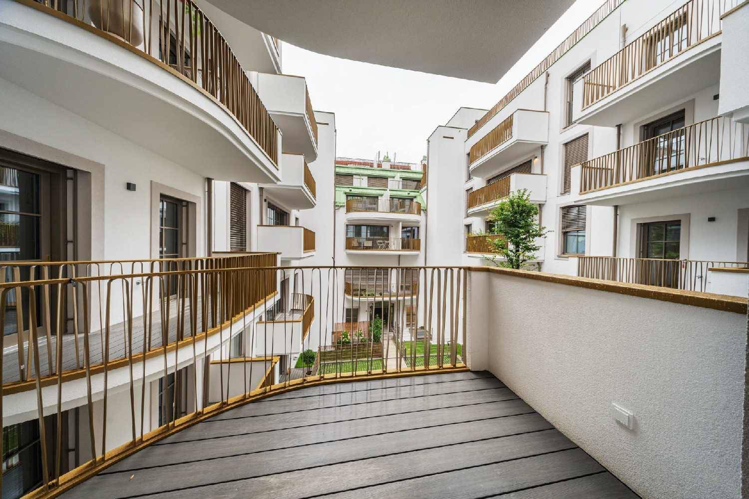 Geschwungener Balkon mit Holzbelag und Blick auf den Innenhof des Gebäudes.