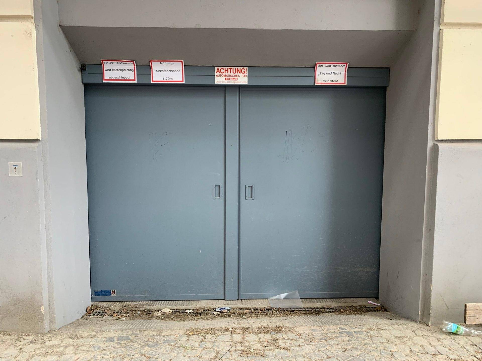 Einfahrt zur Tiefgarage mit großem Rolltor und Hinweisschildern zur Durchfahrtshöhe.