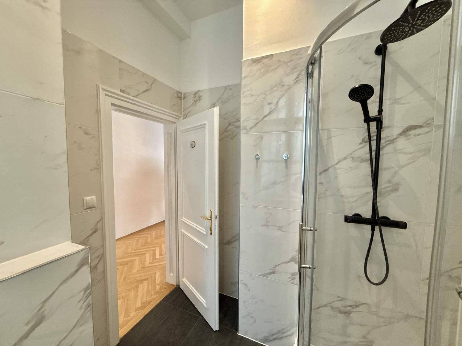 Duschbereich im modernen Badezimmer mit schwarzer Regendusche und eleganten Marmorfliesen.