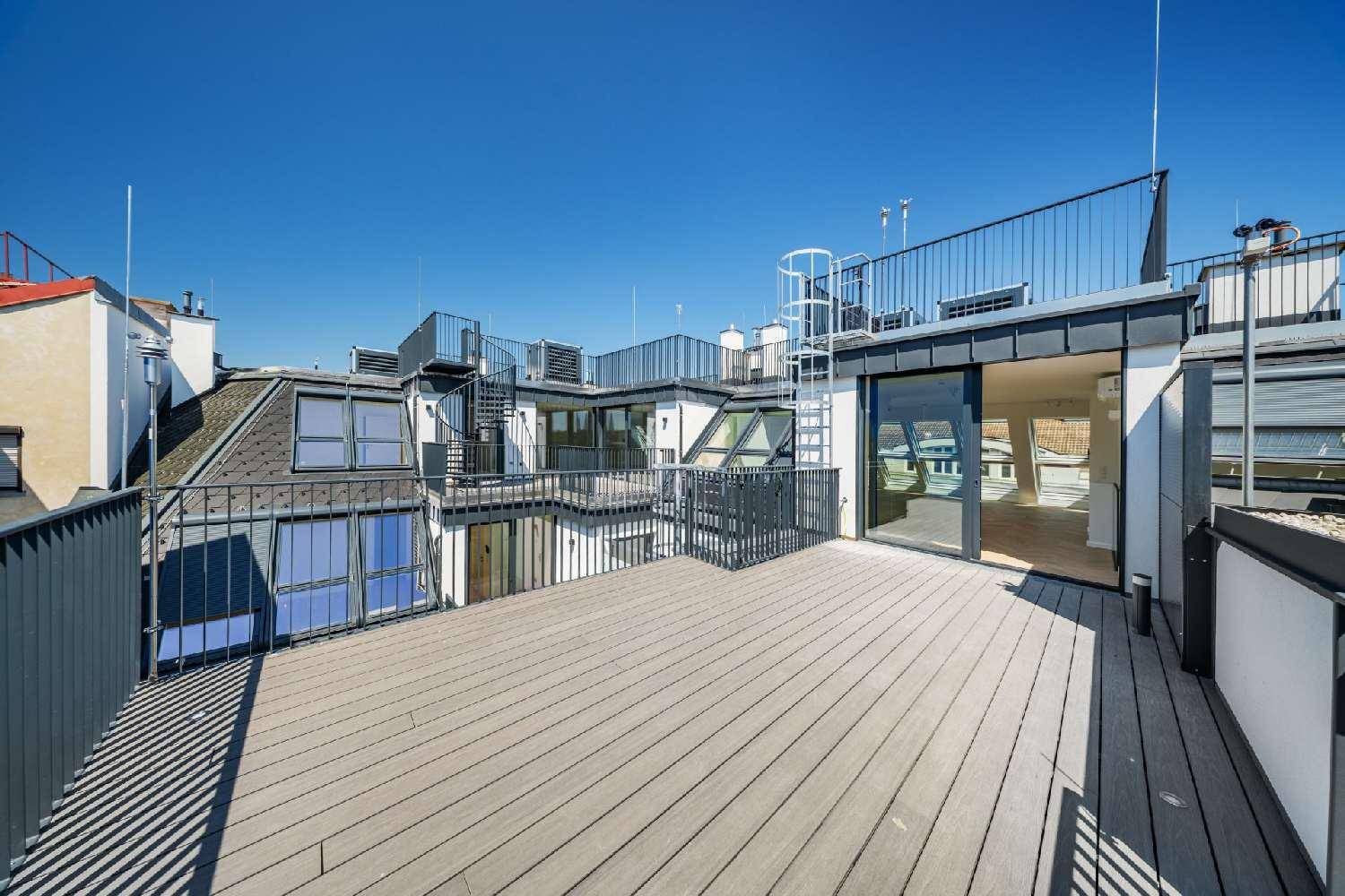 Großzügige Dachterrasse mit Holzdeck und Metallgeländer, die einen weiten Blick über die Stadt bietet.