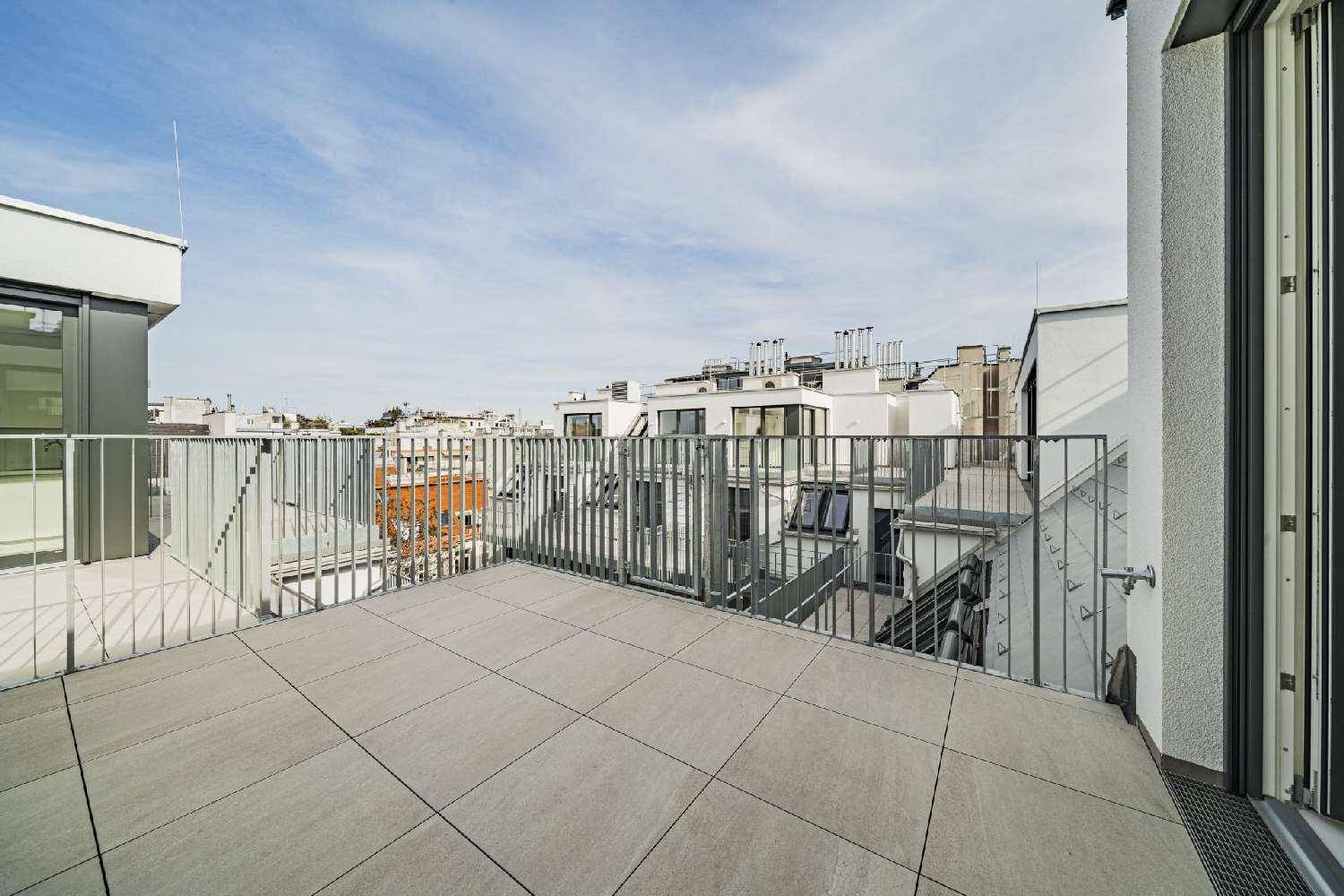 Weitläufige Dachterrasse mit Fliesen und Blick auf die umliegenden Gebäude und den Himmel.