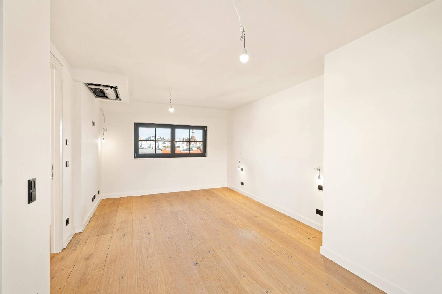 Ruhiges Zimmer mit Holzboden und einem Fenster, das viel Tageslicht hereinlässt.