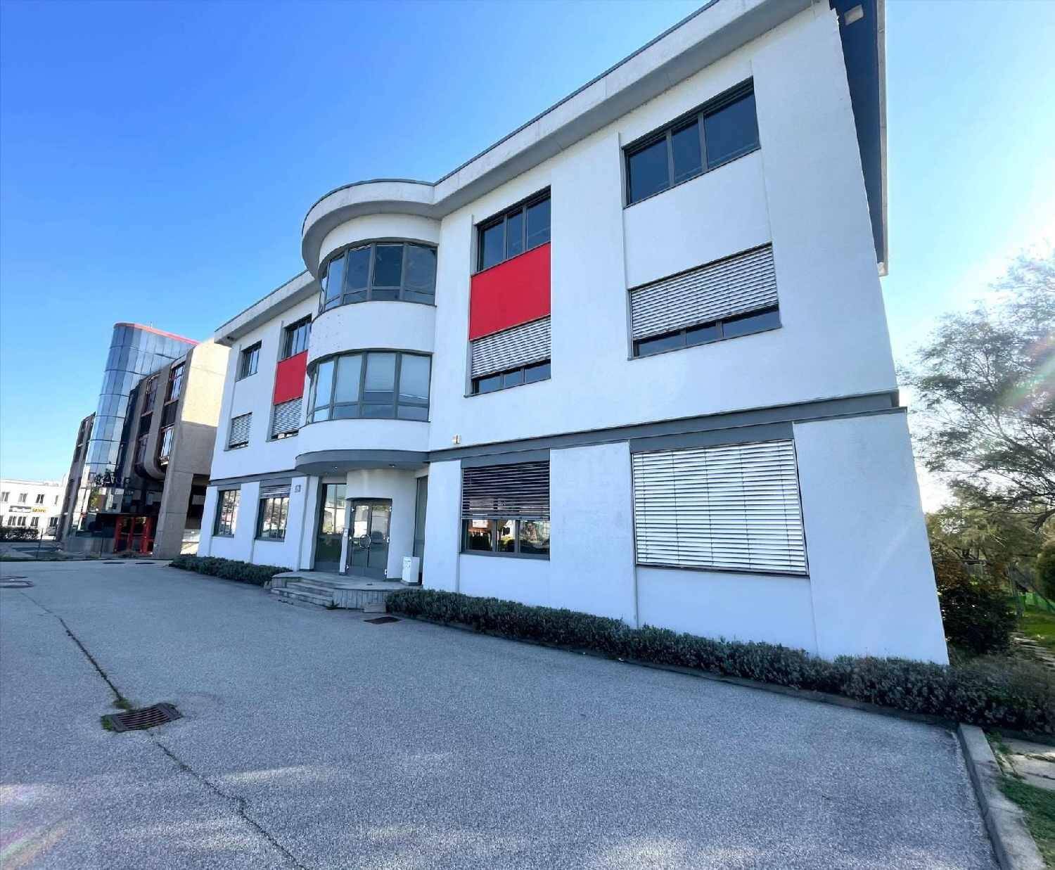 Modernes Bürogebäude mit weißer Fassade, roten Akzenten und großen Fenstern.