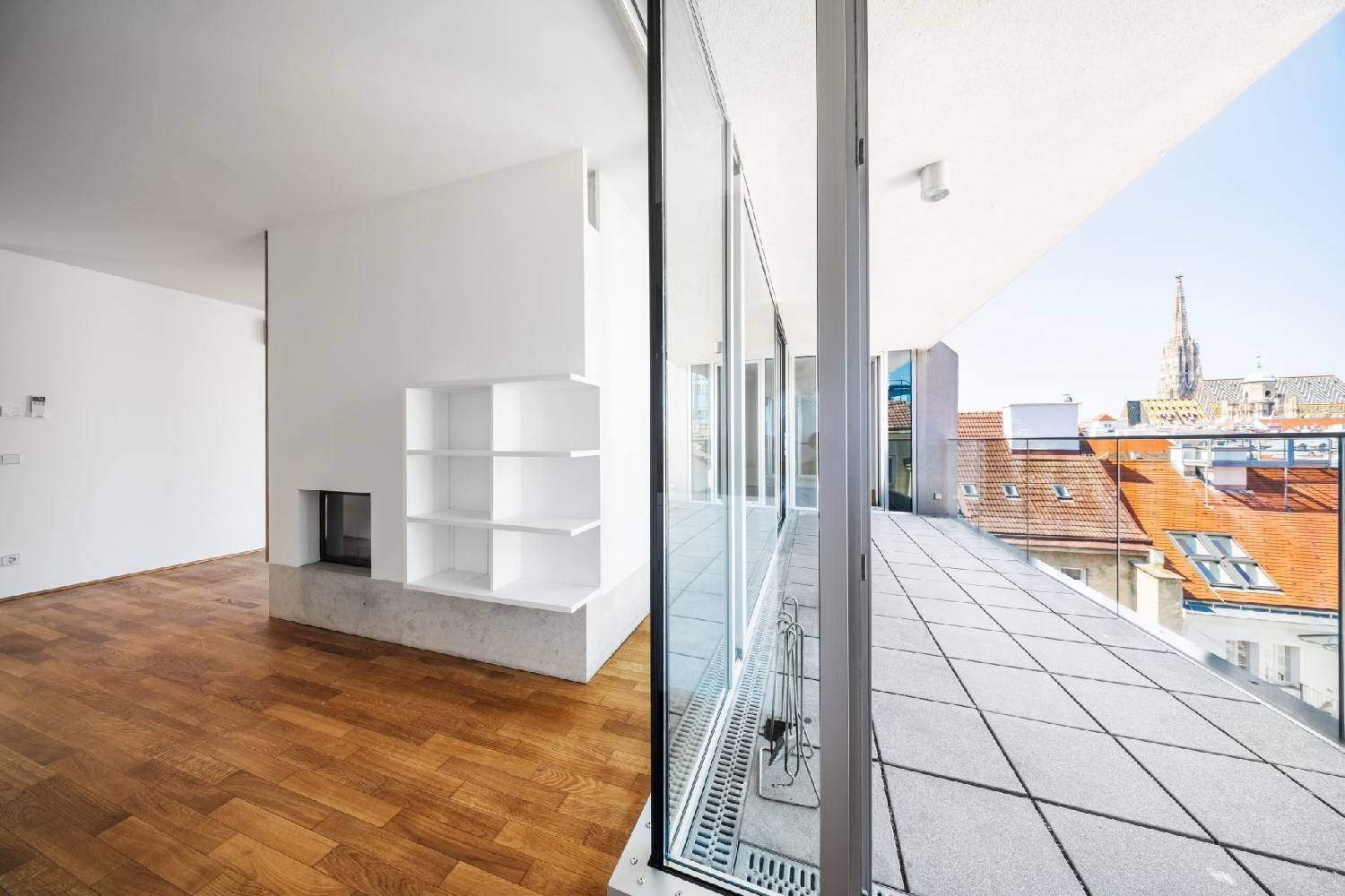 Innenansicht eines Raumes mit Kamin und Zugang zu einer großen Terrasse mit Stadtblick.