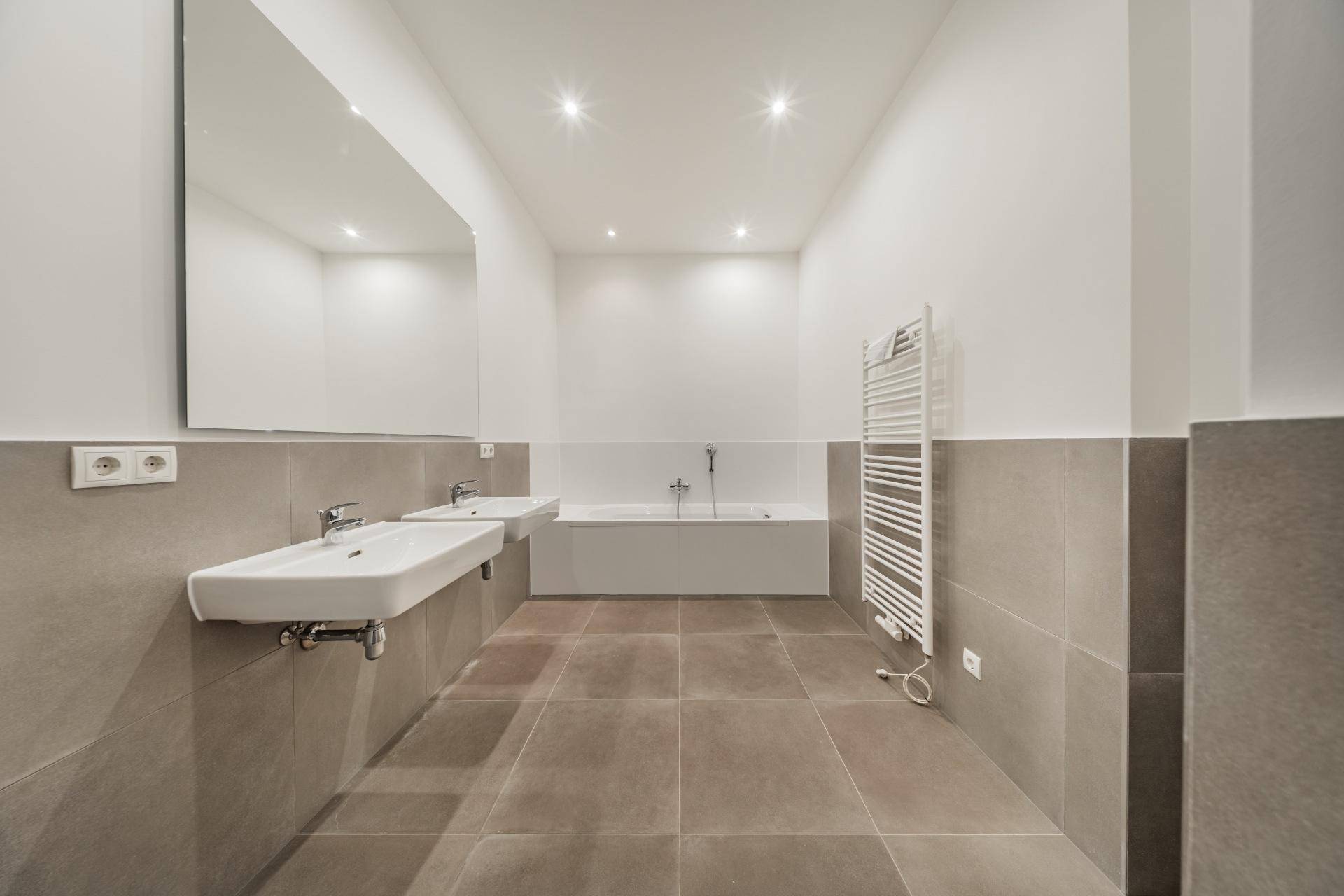 Helles Badezimmer mit zwei Waschbecken, Badewanne und großem Spiegel, in gutem Zustand.