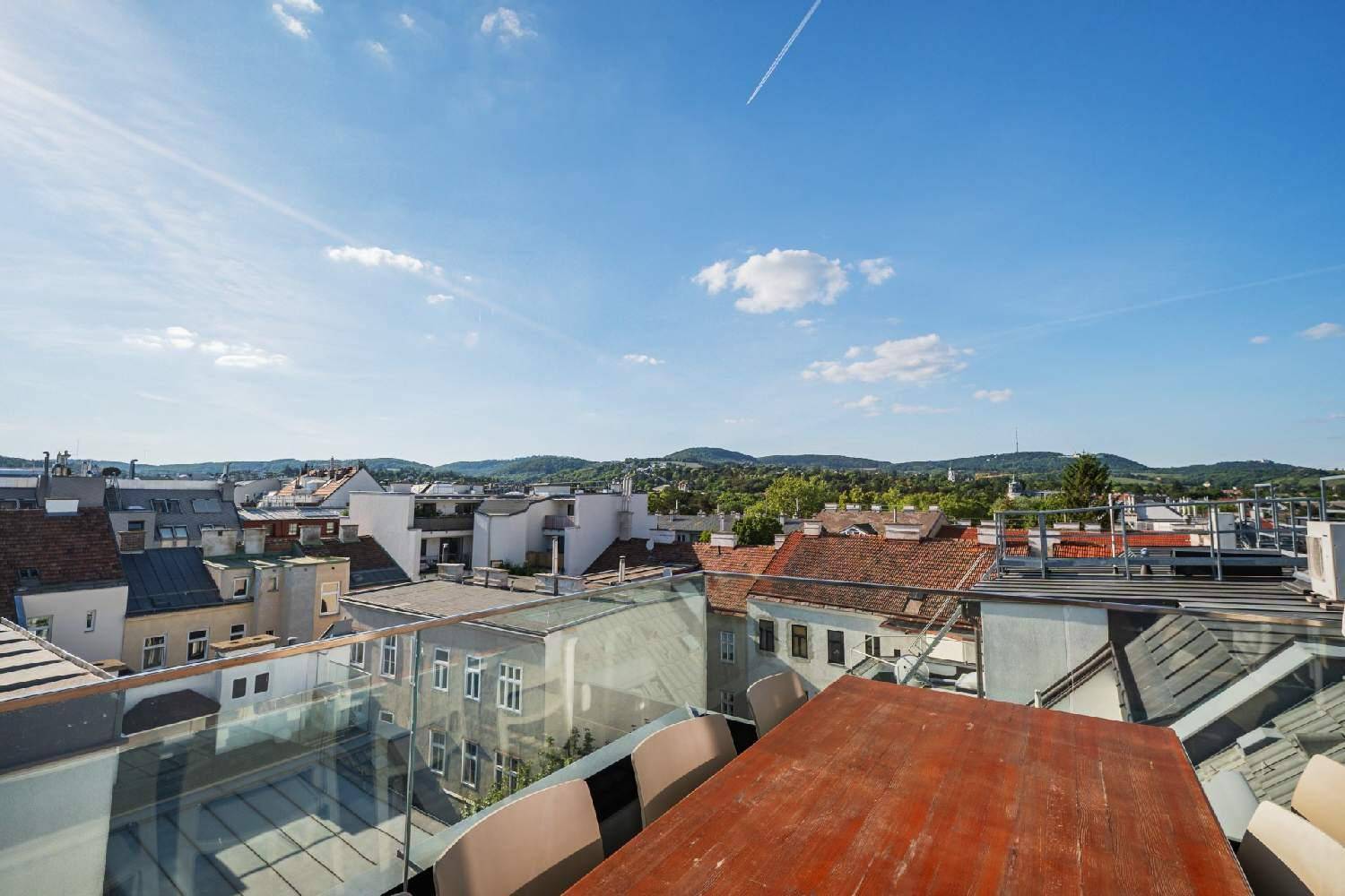 Dachterrasse mit Esstisch und weitem Blick über die Stadt und die umliegende Landschaft.