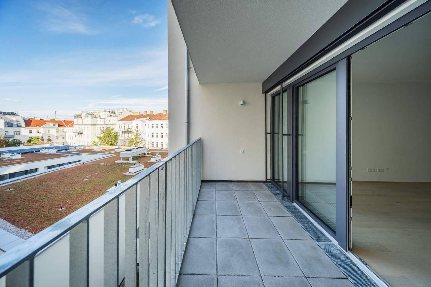 Geräumiger Balkon mit Fliesenboden und Blick auf begrünte Dächer und die Stadt.