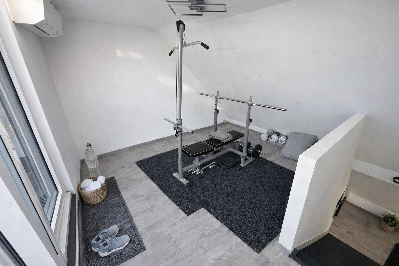 Kleiner Fitnessbereich mit Trainingsgeräten unter dem Dach, ideal für das Heimtraining.