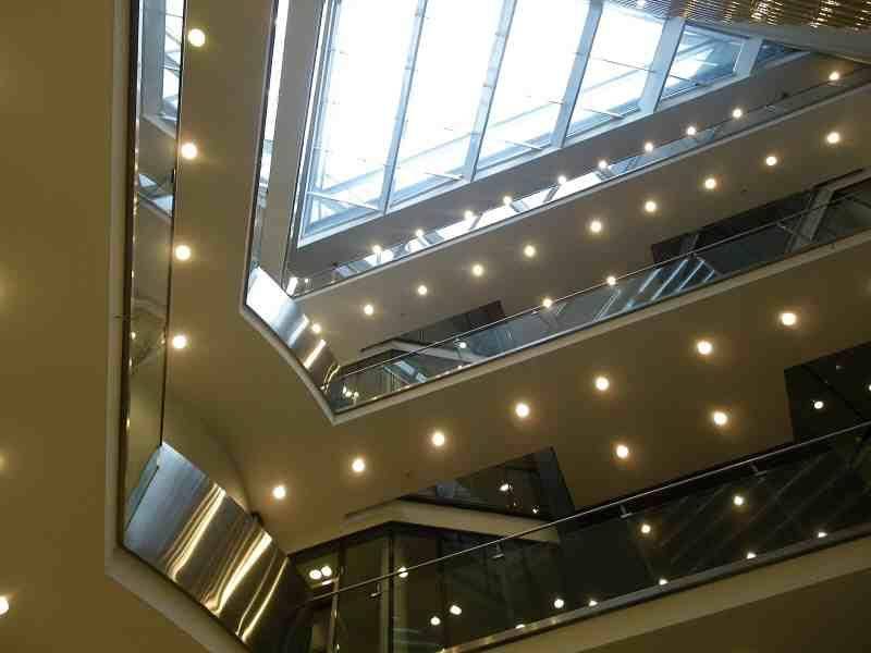 Heller Atrium-Bereich mit Glasdach, mehreren Etagen und modernen Beleuchtungselementen.