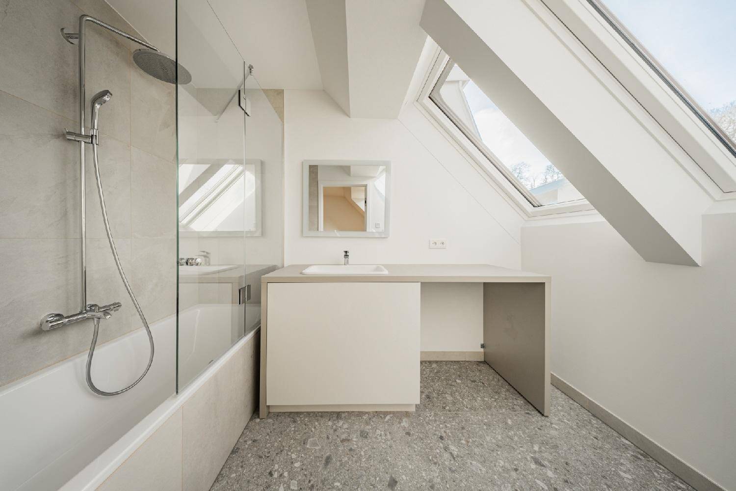 Helles Badezimmer mit Badewanne, Dusche, Waschtisch und schrägem Dachfenster.