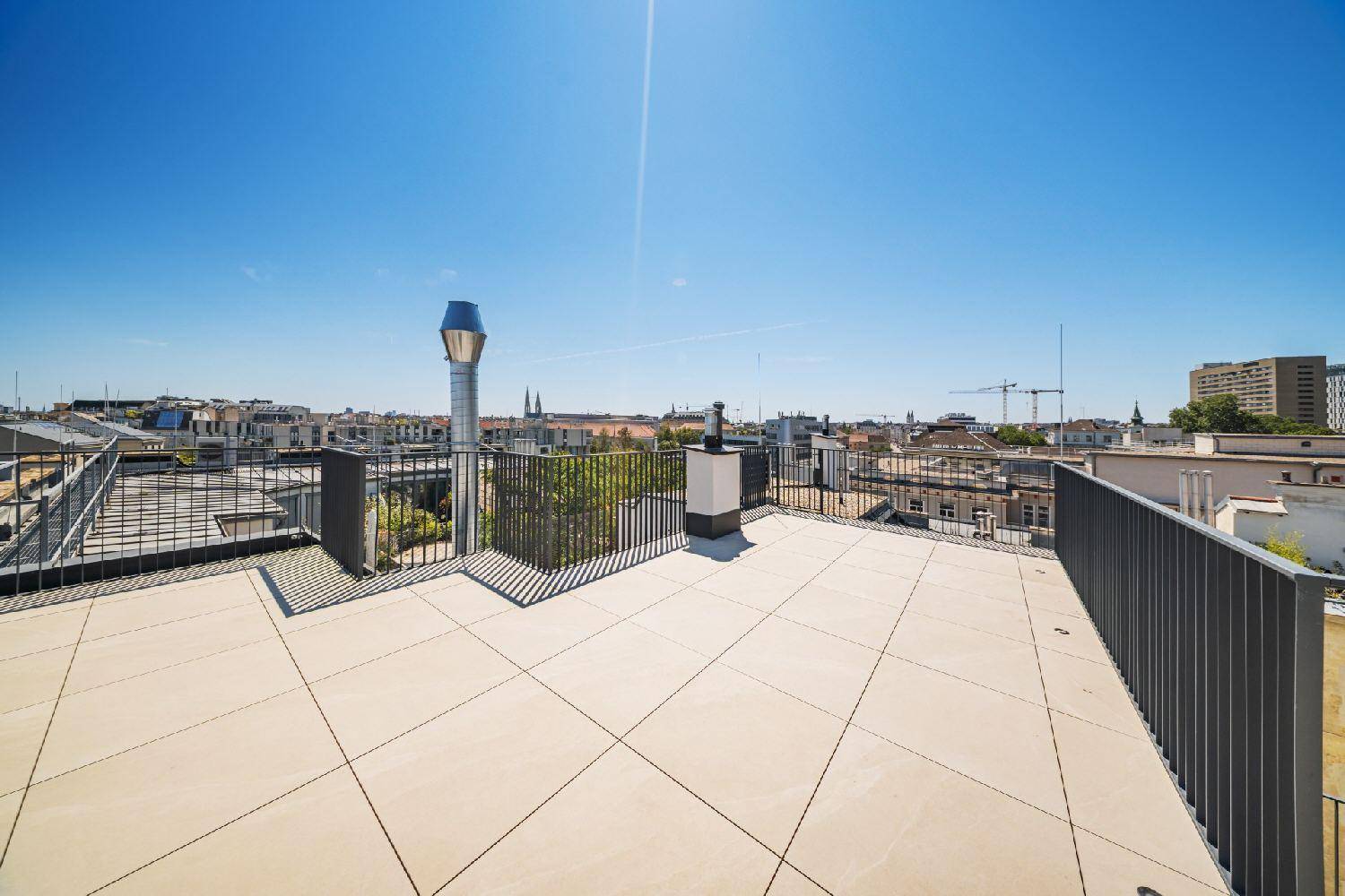 Obere Dachterrasse mit Fliesenboden und einem beeindruckenden Weitblick über die Dächer der Stadt.