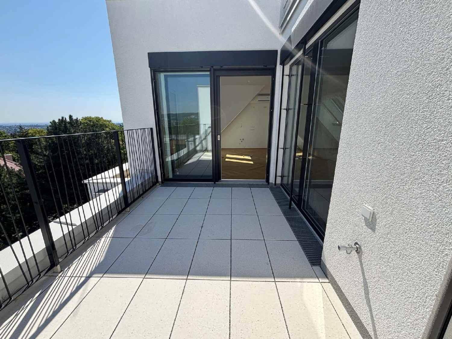 Heller Balkon mit Fliesenboden, schwarzem Geländer und weitem Blick ins Grüne.