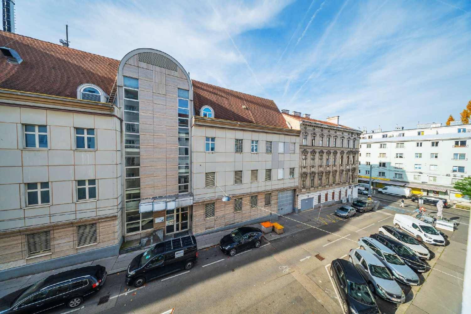 Weitläufiger Blick über eine Stadtstraße mit historischen und modernen Gebäuden unter blauem Himmel.