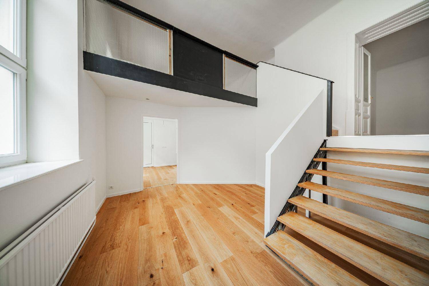 Eingangsbereich mit Holztreppe und Galerie, die zu weiteren Räumen führt.