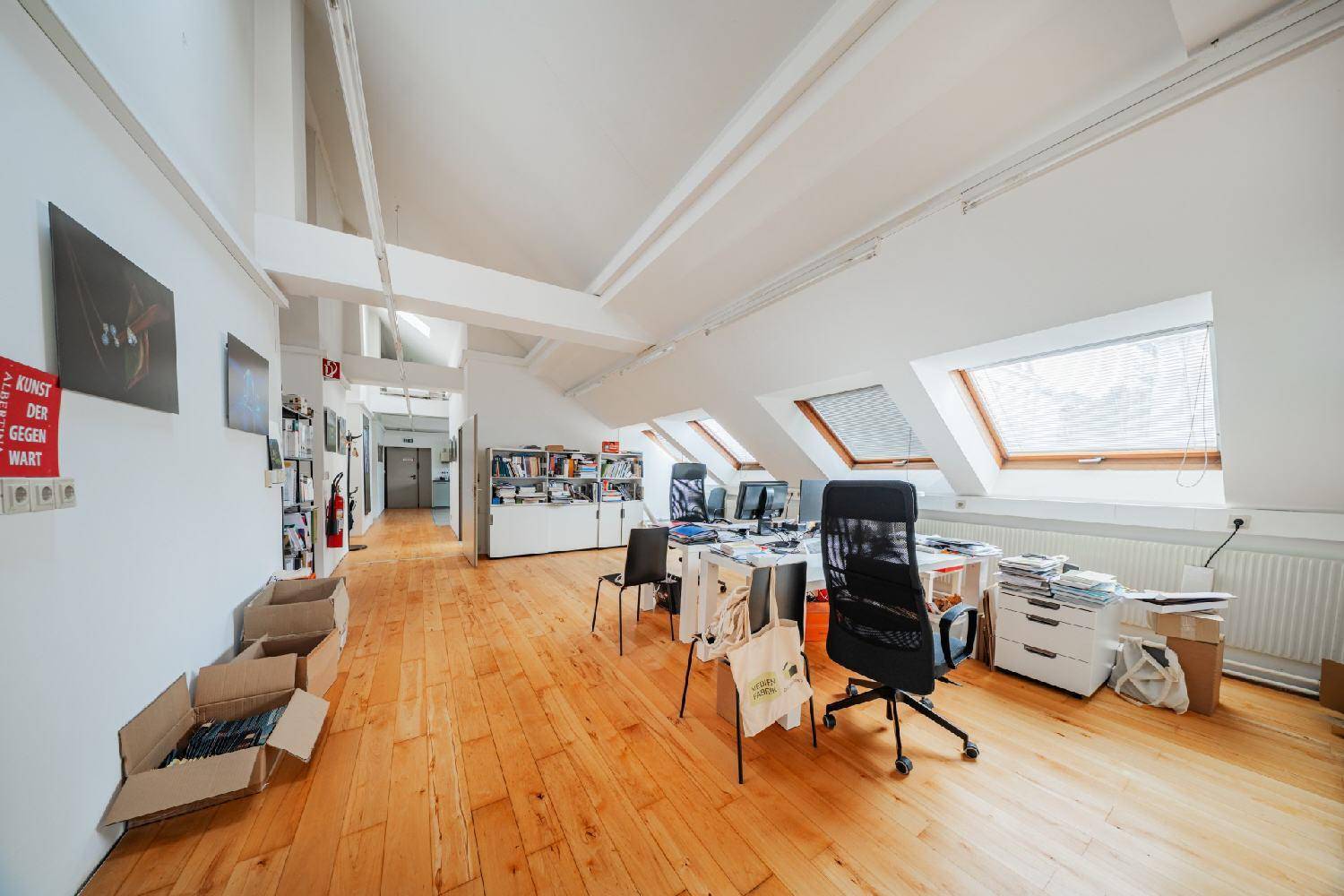 Helles Dachgeschossbüro mit Holzboden, Arbeitsplätzen und schrägen Decken, bietet eine einzigartige Atmosphäre.