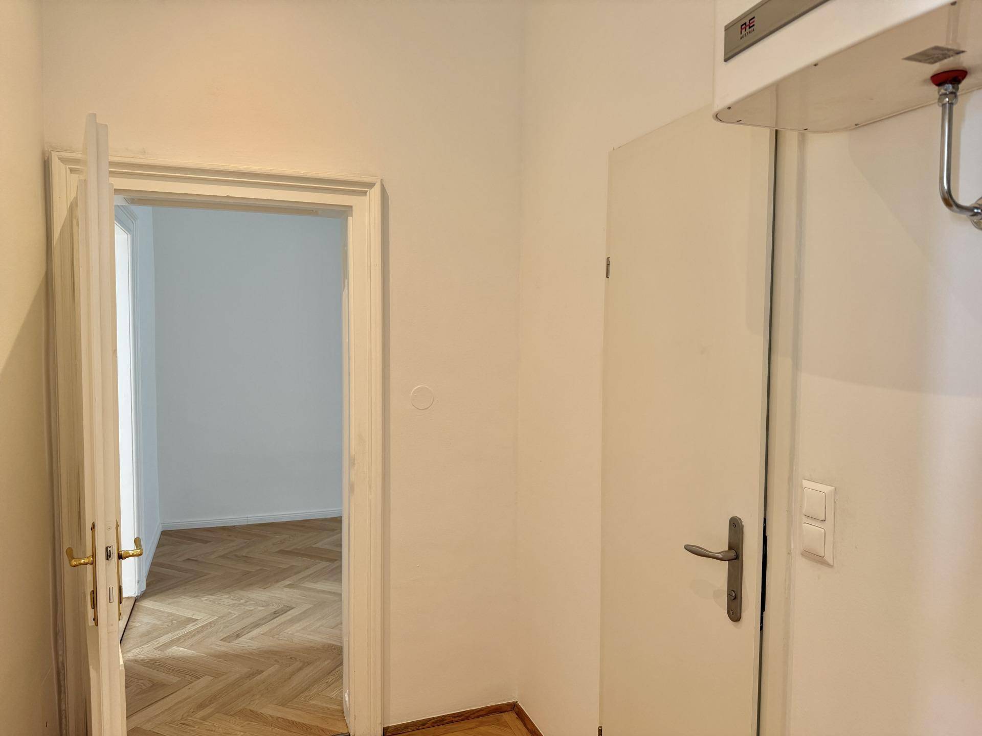 Heller Flur mit Fischgrätparkettboden und Zugang zu verschiedenen Räumen der Wohnung.