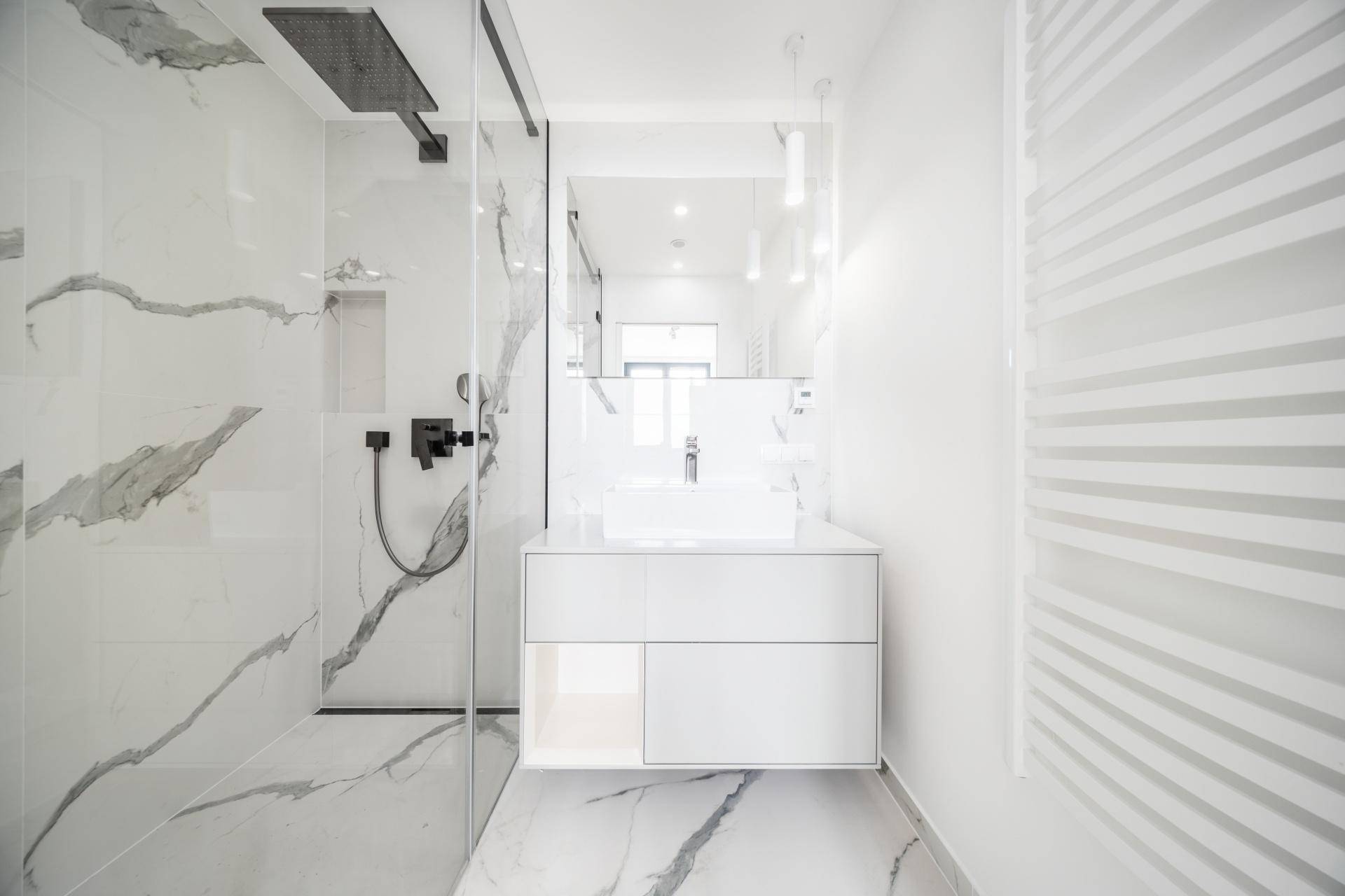 Modernes Badezimmer mit Marmorfliesen, begehbarer Dusche und elegantem Waschtisch mit Spiegel.