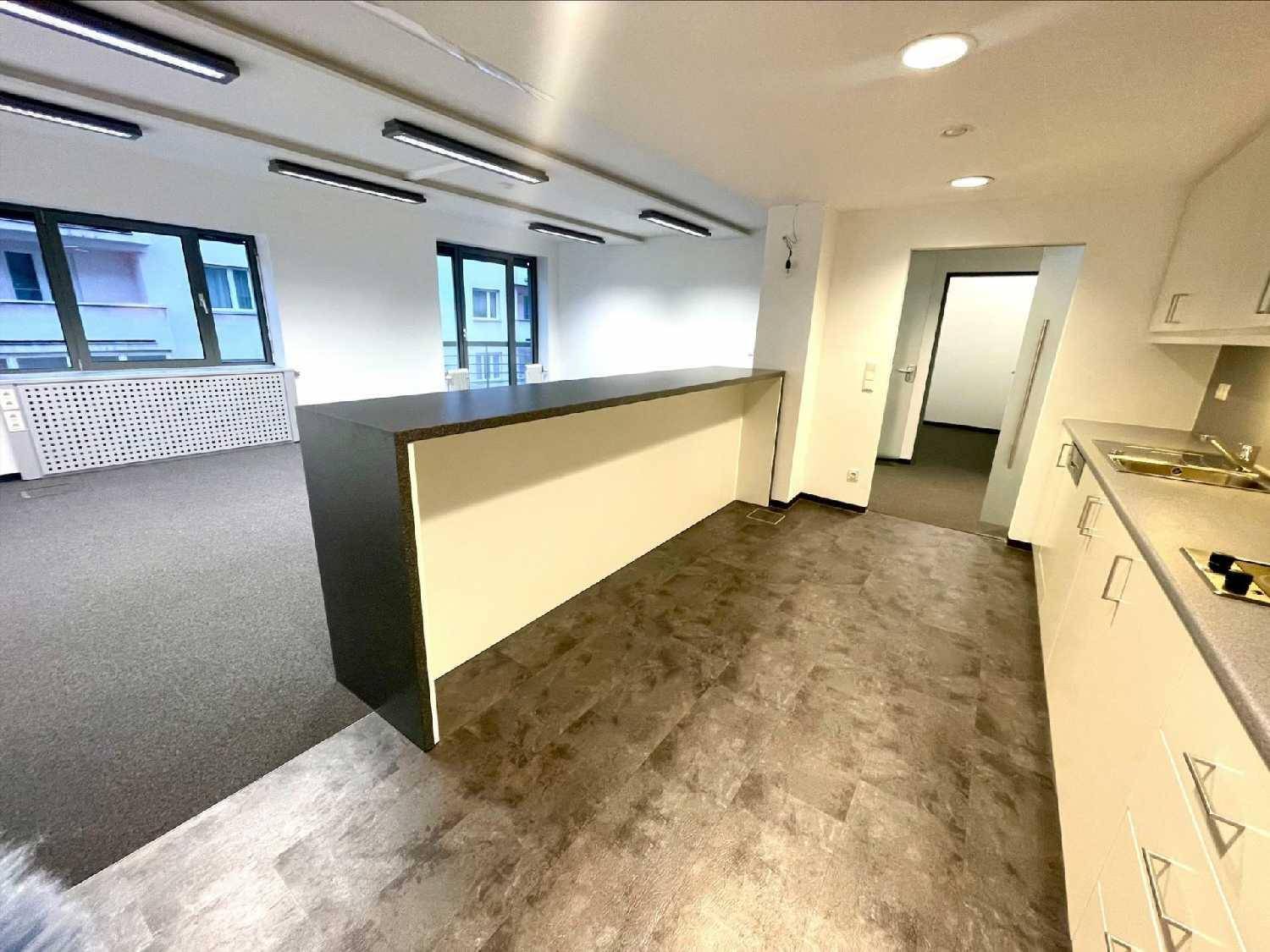 Offener Bürobereich mit Theke und angrenzender Küchenzeile, Teppich- und Vinylboden.