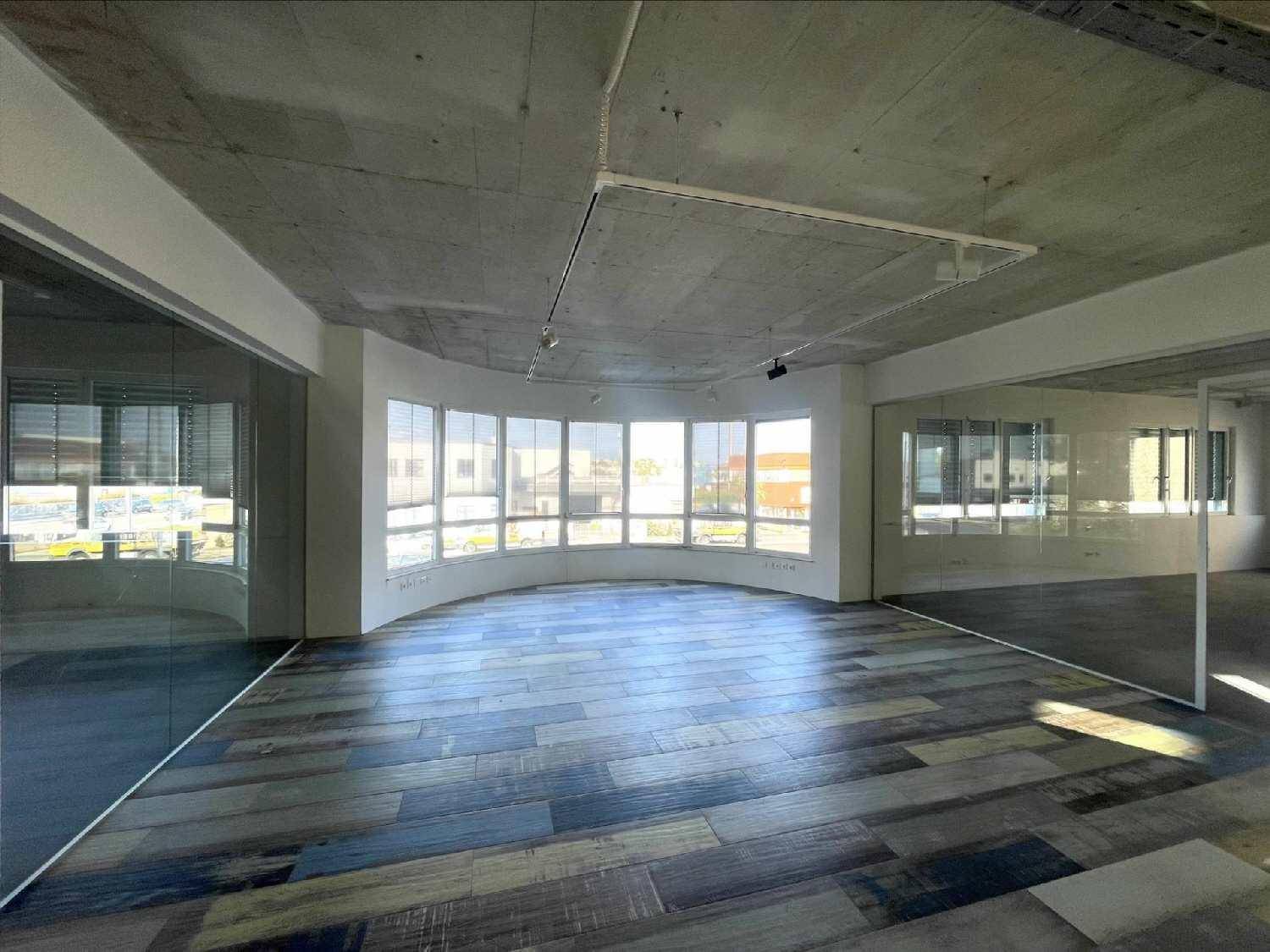Großes, leeres Büro mit geschwungener Fensterfront, Sichtbetondecke und modernem Holzboden.
