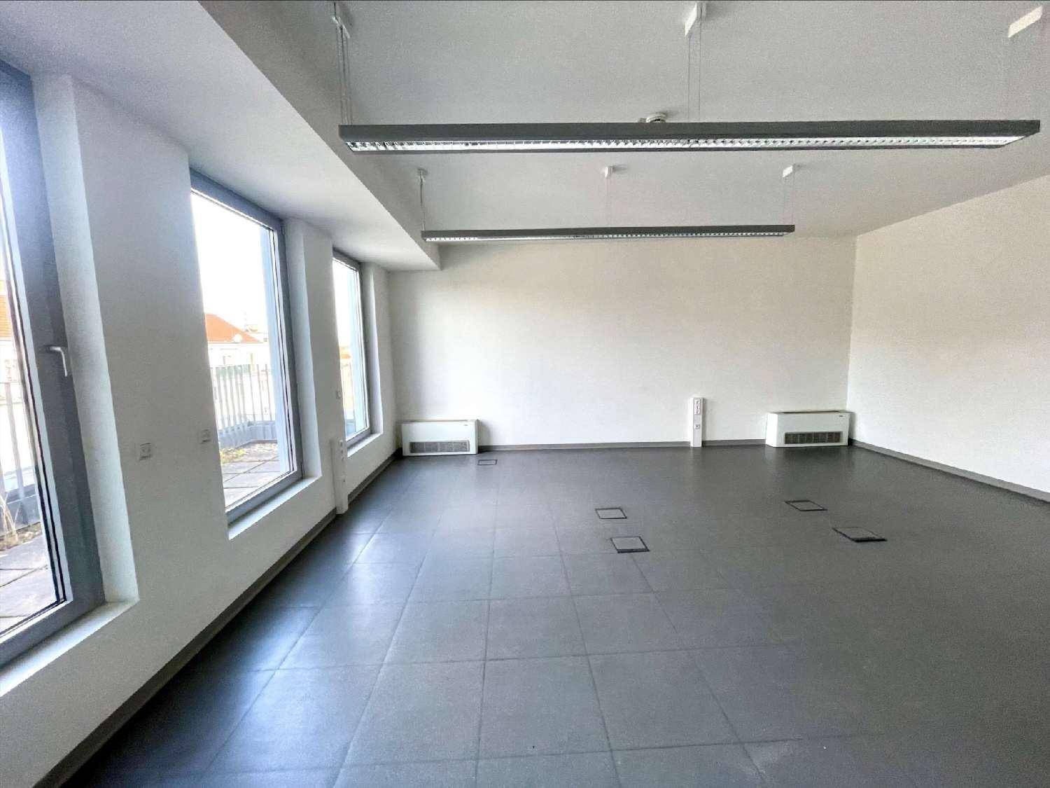 Geräumiger Büroraum mit großen Fenstern, die Zugang zu einer Terrasse bieten und viel natürliches Licht hereinlassen.