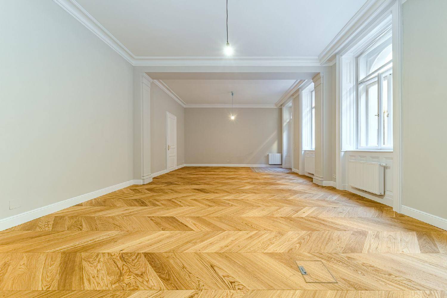 Heller, leerer Raum mit elegantem Fischgrätparkett und hohen Decken, bereit für die individuelle Gestaltung.