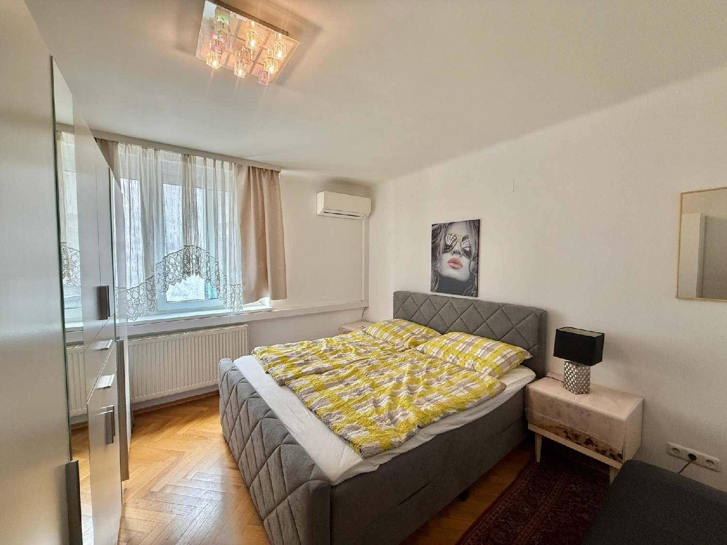 Schlafzimmer mit Doppelbett, Fischgrätparkett, Klimaanlage und großem Fenster.