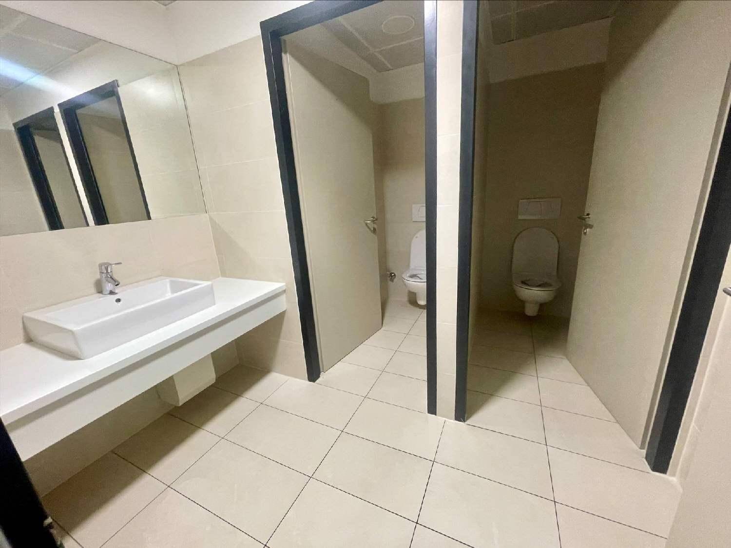 Moderne Toilettenanlage mit Fliesenboden, Waschbecken und zwei separaten Kabinen.