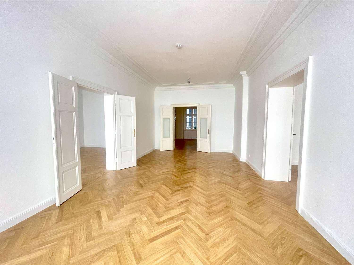 Weitläufiger Wohnraum mit elegantem Fischgrätparkett und hohen Decken, der eine offene Atmosphäre schafft.