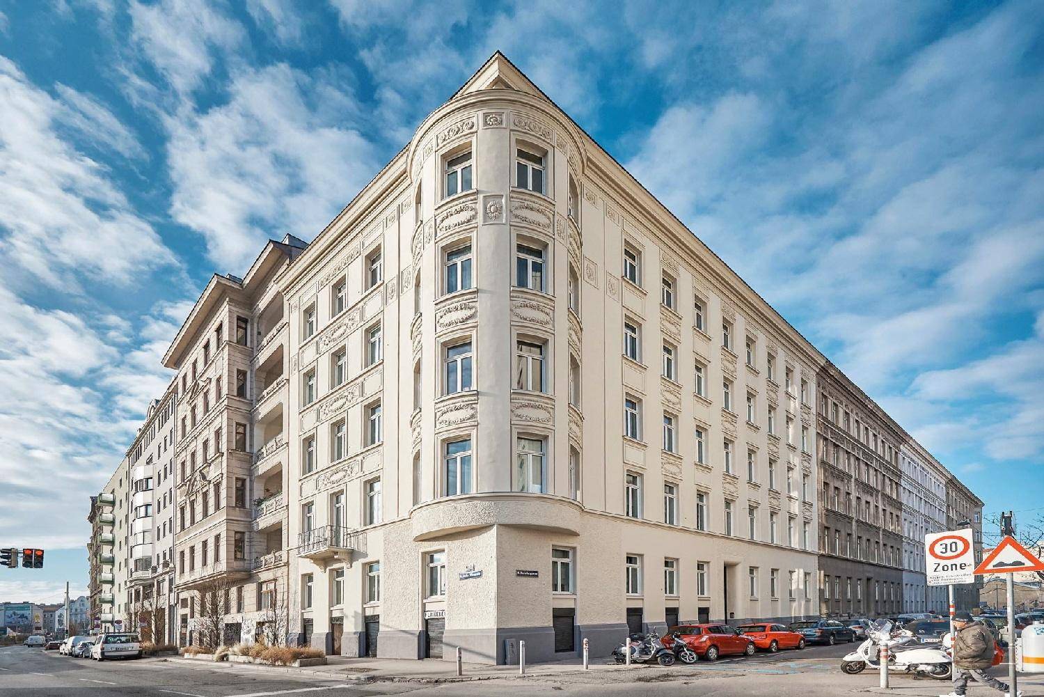 Eindrucksvolles Eckgebäude mit klassischer Architektur und vielen Fenstern unter blauem Himmel.
