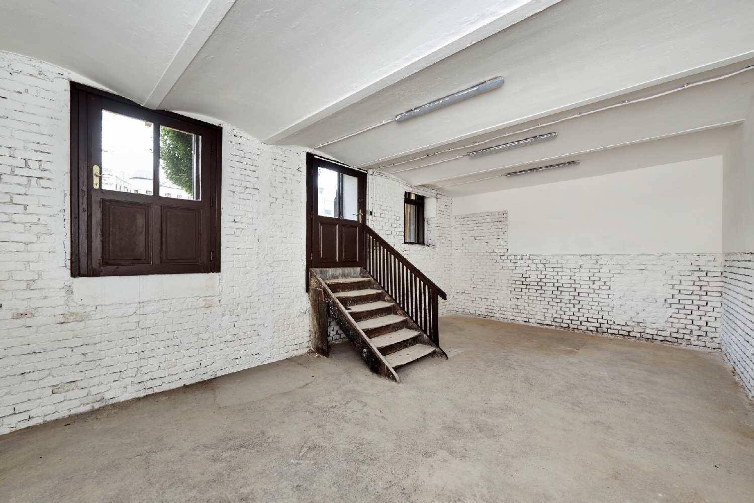 Heller Lagerraum mit Holztreppe, zwei Fenstern und Deckenbeleuchtung, bereit zur individuellen Gestaltung.
