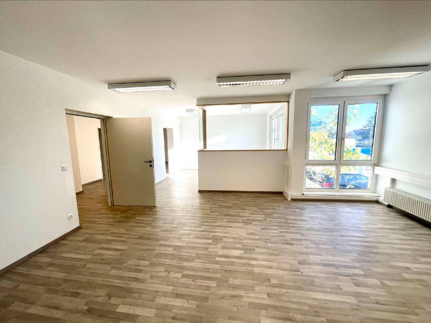 Heller Büroraum mit Holzoptikboden und großen Fenstern, die viel Tageslicht hereinlassen und eine angenehme Atmosphäre schaffen.