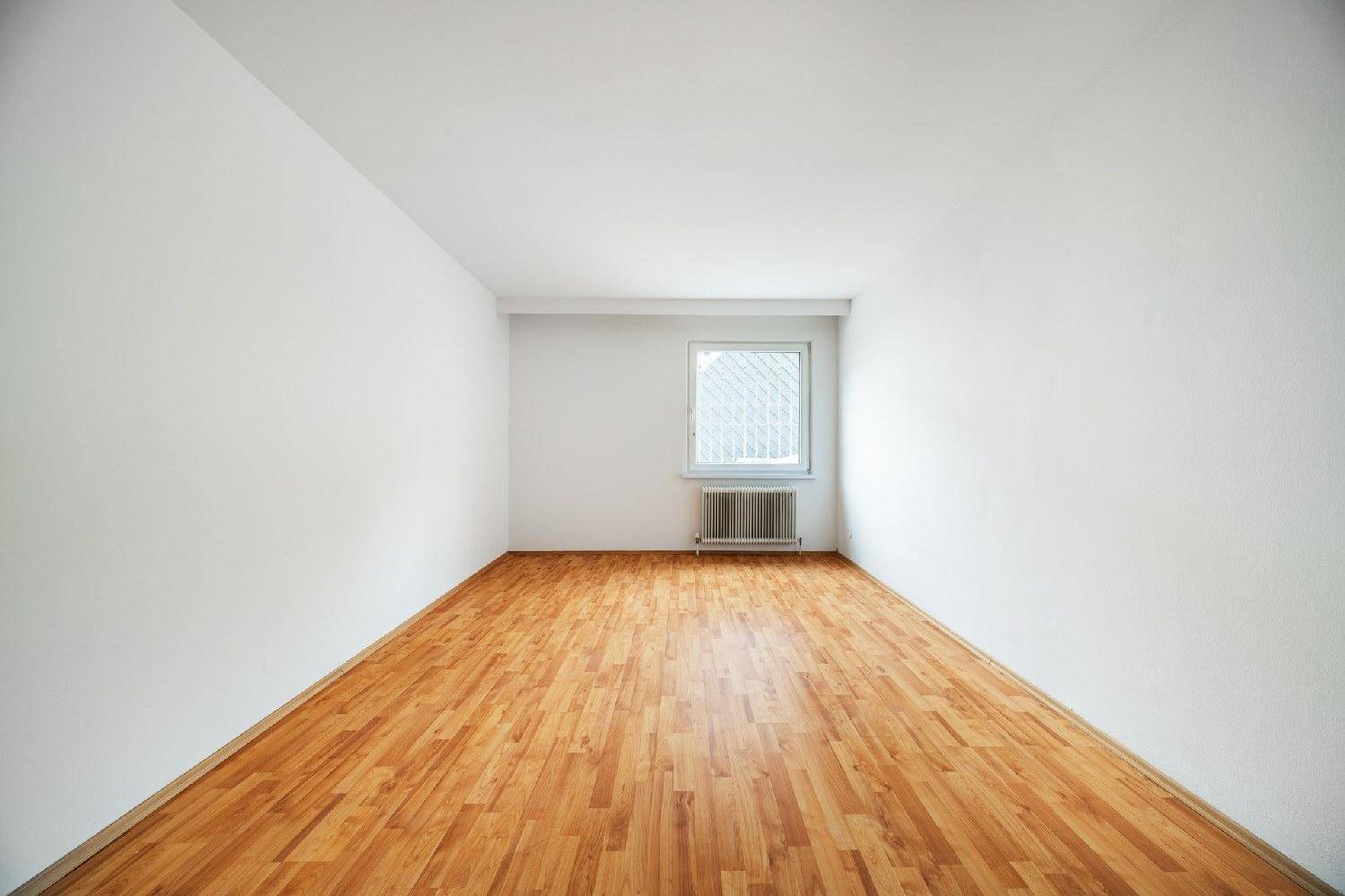 Geräumiges Zimmer mit Laminatboden und Fenster, ideal für ein Schlaf- oder Kinderzimmer.