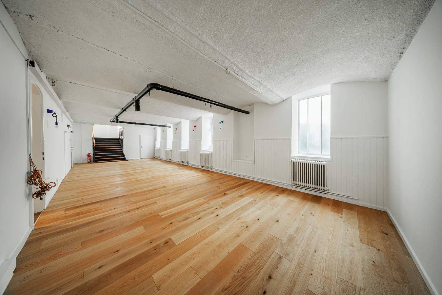 Großer Raum mit Holzboden, strukturierten Decken und sichtbaren Rohren, der vielseitig nutzbar ist.