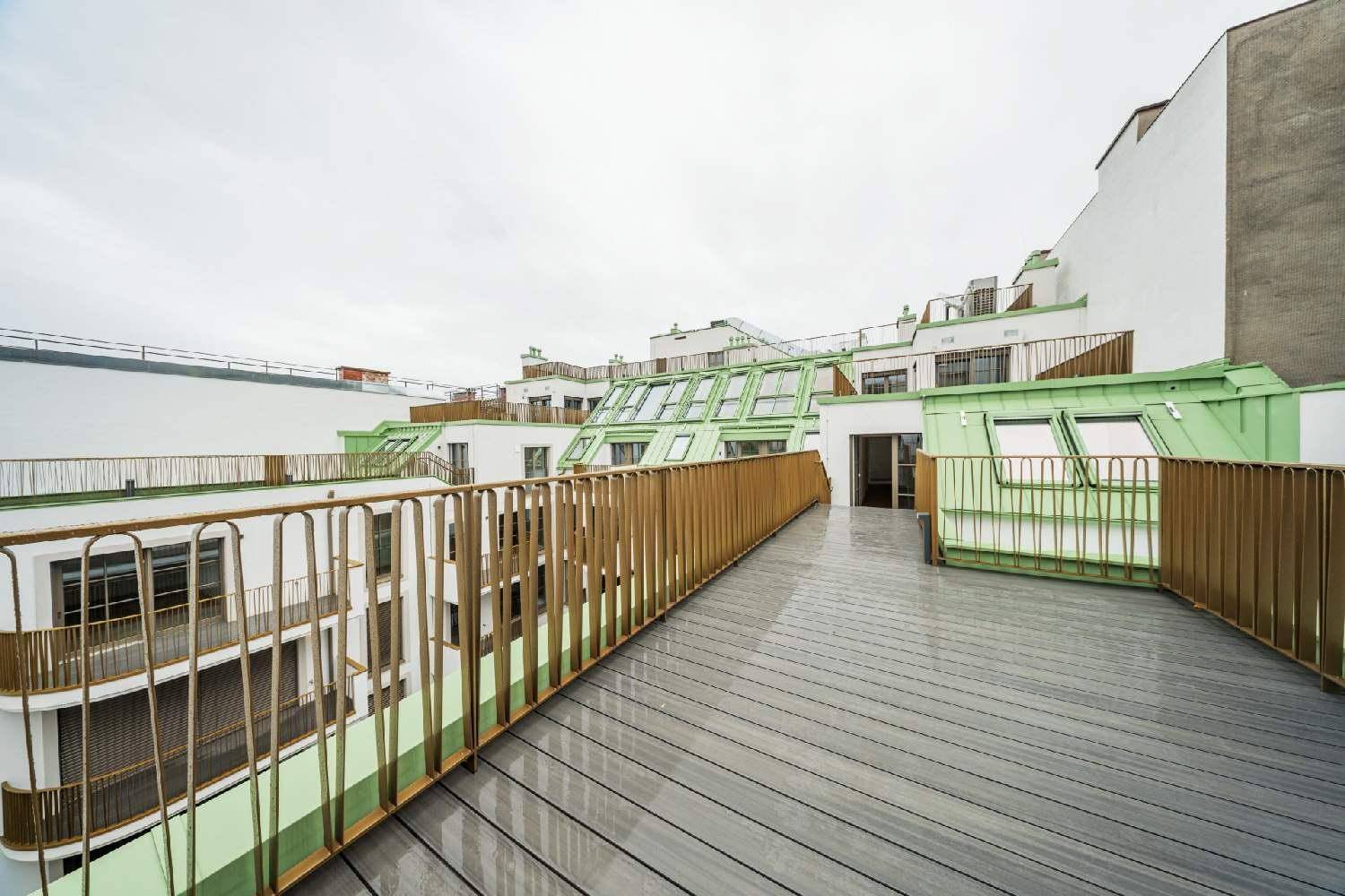 Weitläufige Dachterrasse mit modernen goldenen Geländern und Blick auf die umliegenden Gebäude.