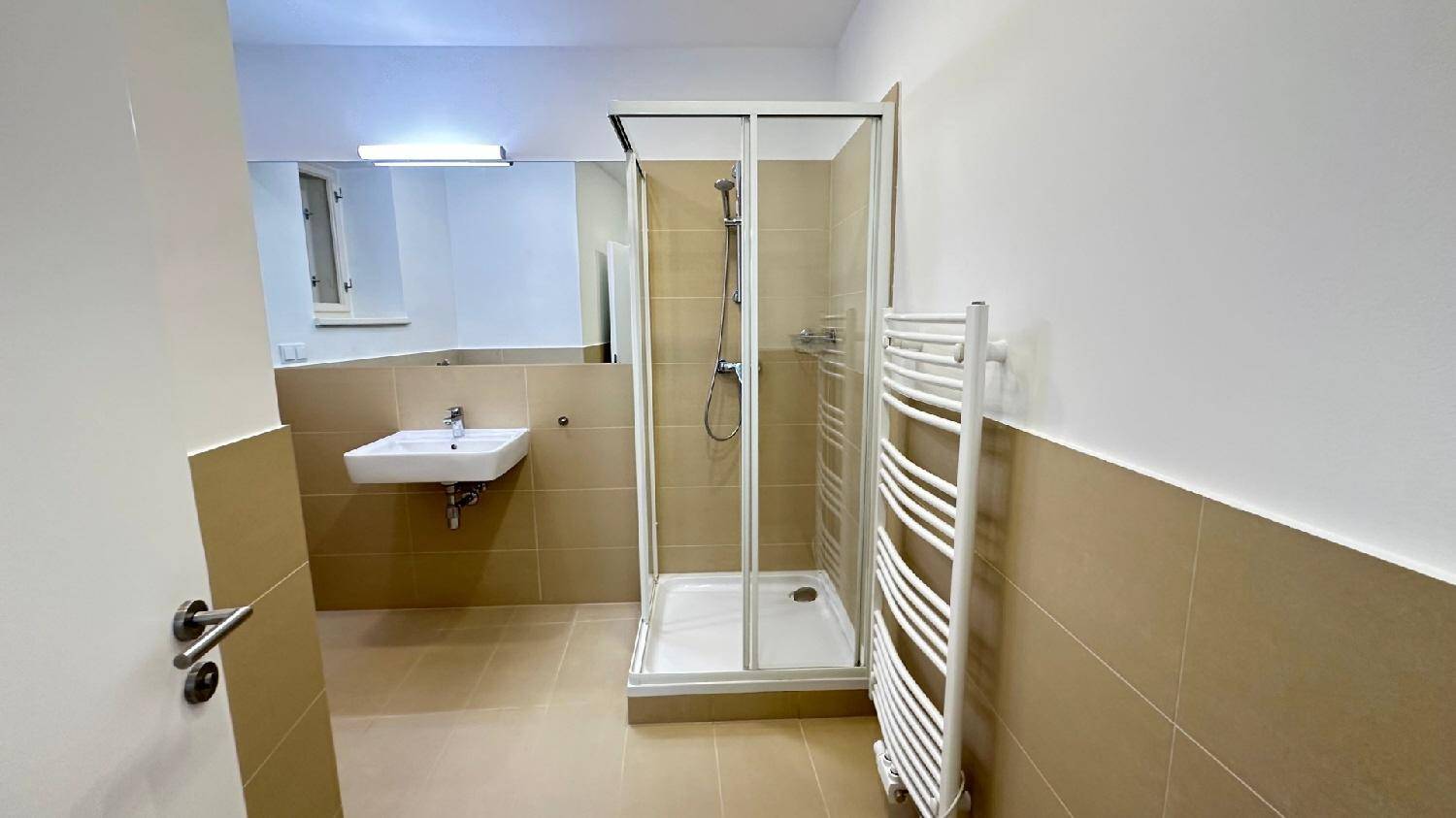 Modernes Badezimmer mit Dusche, Waschbecken und beheiztem Handtuchhalter in neutralen, hellen Farbtönen.