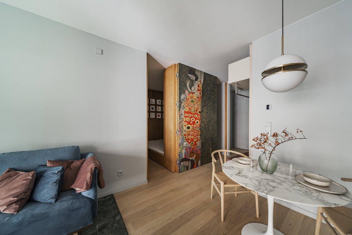 Essbereich mit Marmortisch und Zugang zu einem clever integrierten Schlafbereich hinter einer Kunstwand.