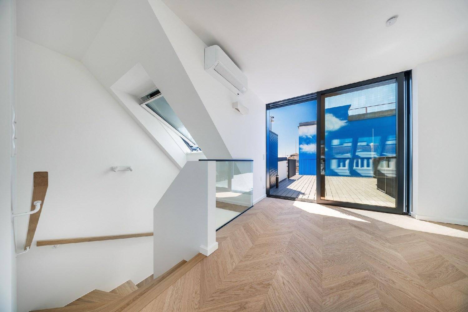 Moderner Treppenaufgang mit Holzstufen und Glasgeländer, der zum hellen Wohnbereich mit Terrassenzugang führt.