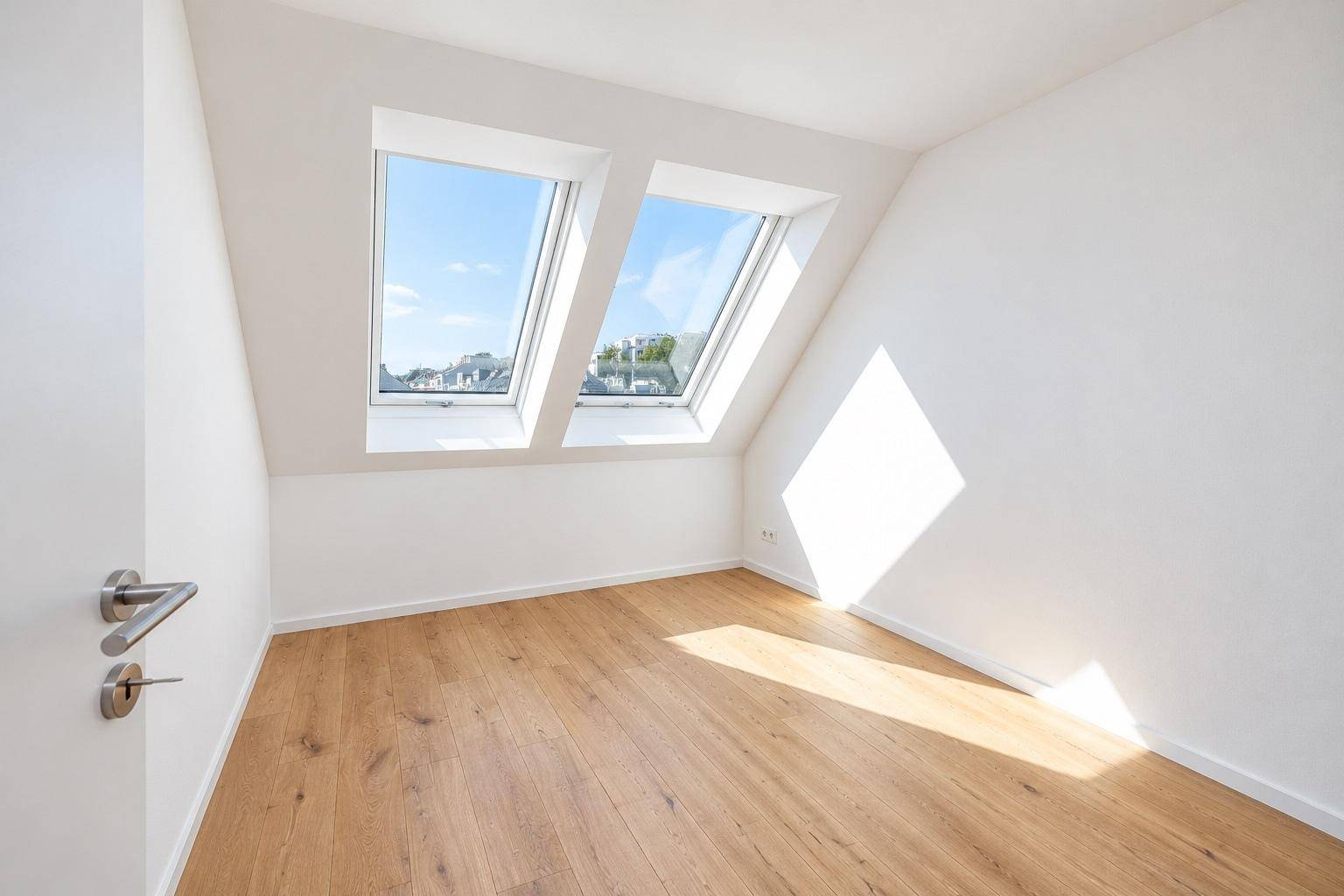 Gemütliches Schlafzimmer im Dachgeschoss mit Holzboden und zwei Dachfenstern, die viel Licht spenden.