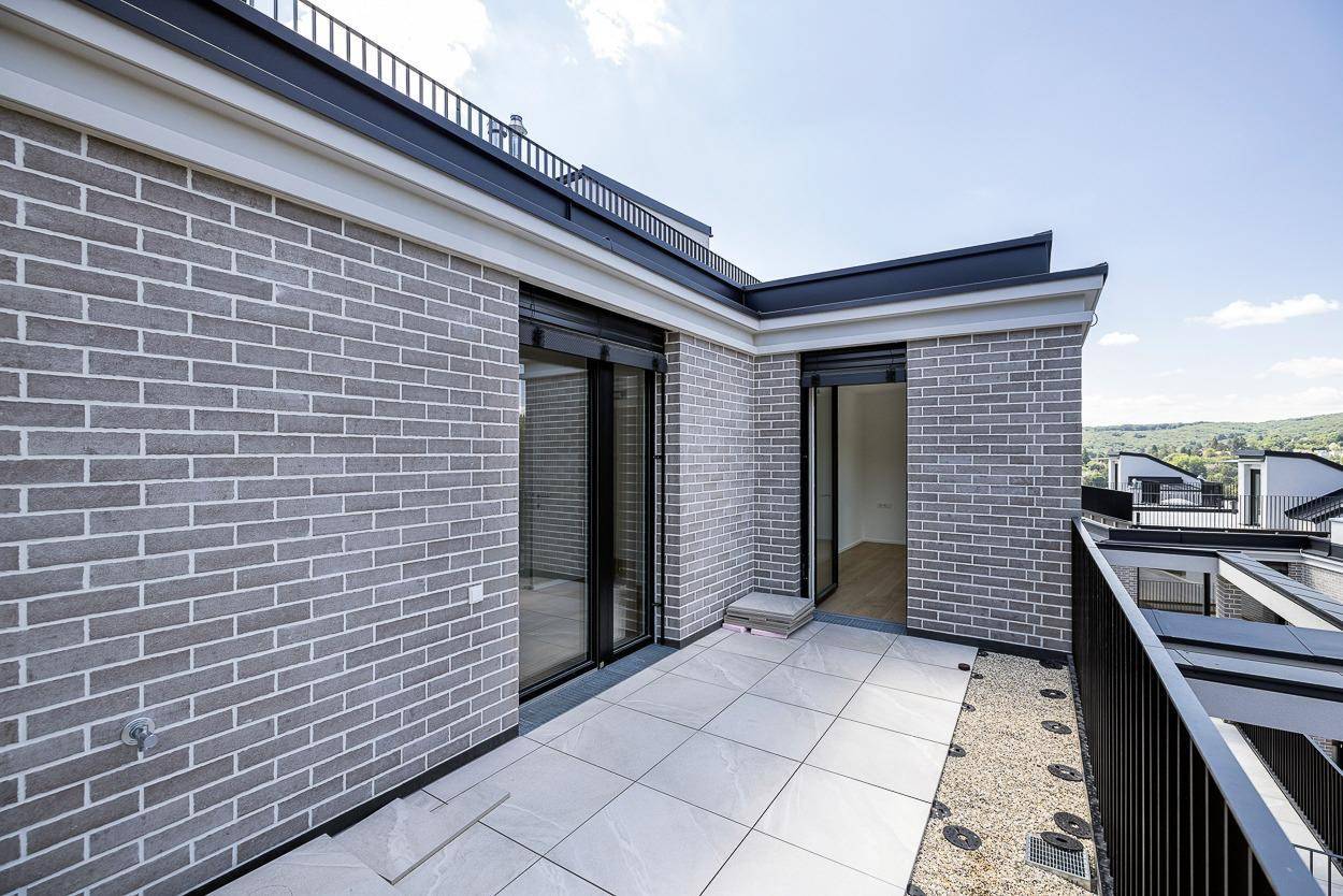 Terrasse mit Ziegelwand und Fliesenboden, bietet Zugang zu Innenräumen.