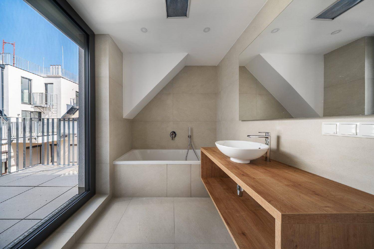 Modernes Badezimmer mit Badewanne, Holzwaschtisch und großem Fenster mit Blick auf den Außenbereich.