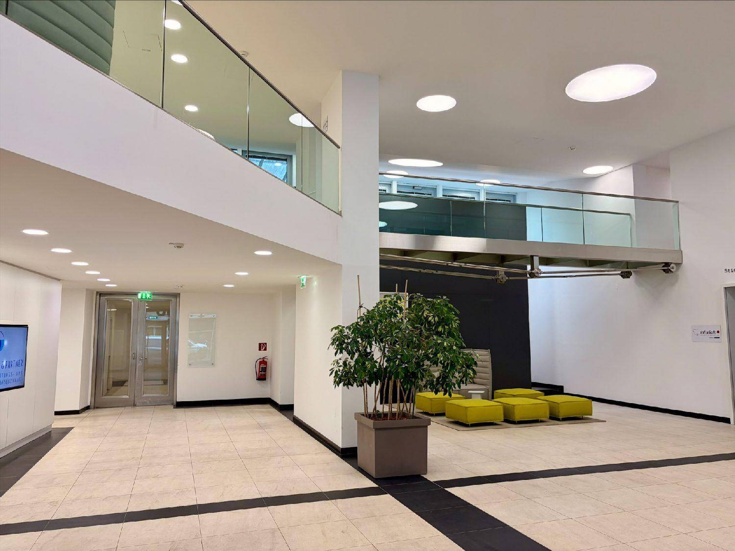 Helle, moderne Lobby mit hohen Decken, Glasgeländern und einer einladenden Sitzgelegenheit.