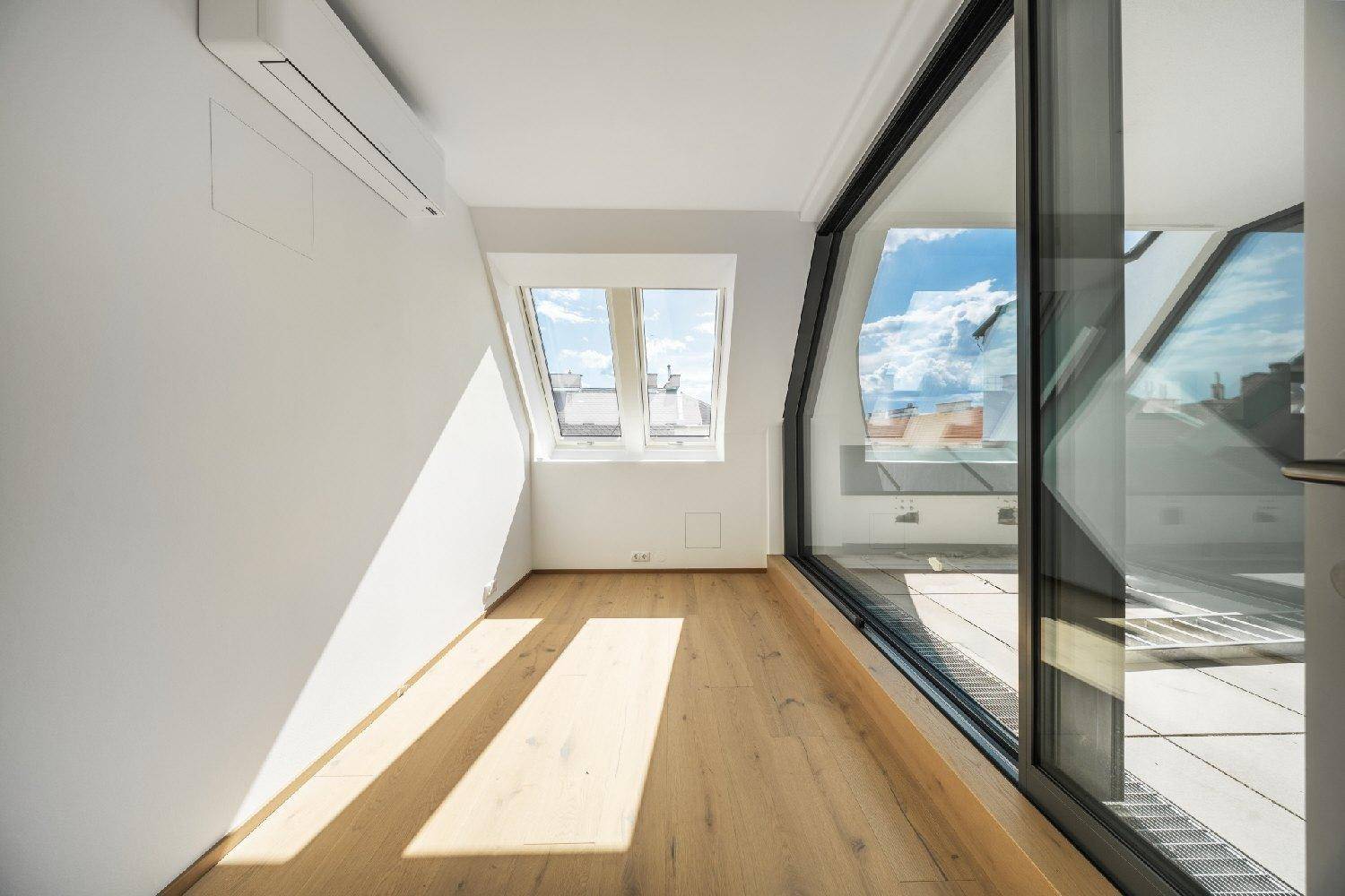 Helles Zimmer mit Holzboden, Dachfenster, Klimaanlage und direktem Zugang zur Terrasse.