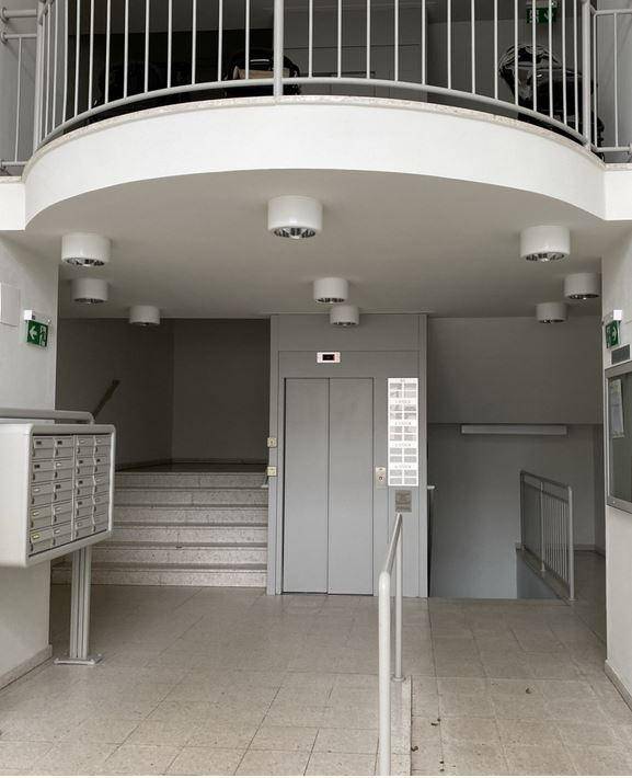 Eingangsbereich eines Gebäudes mit Aufzug, Treppe und Briefkästen, funktional und gut gepflegt.