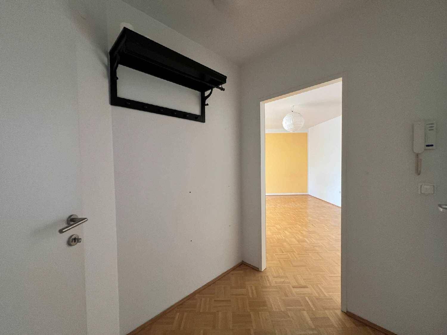 Eingangsbereich mit Parkettboden und Blick in den offenen Wohnbereich mit gelber Akzentwand.
