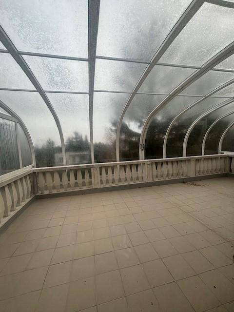 Überdachte Terrasse mit Fliesenboden und transparentem Dach für viel natürliches Licht.