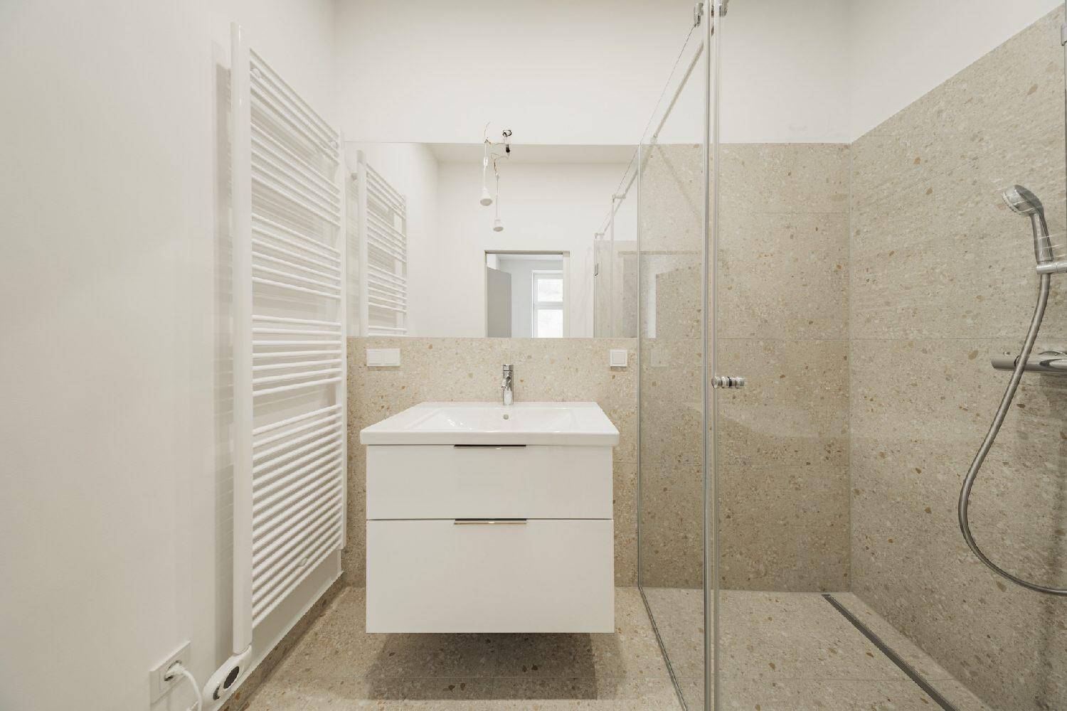 Modernes Badezimmer mit begehbarer Dusche, Waschtisch und beheiztem Handtuchhalter.
