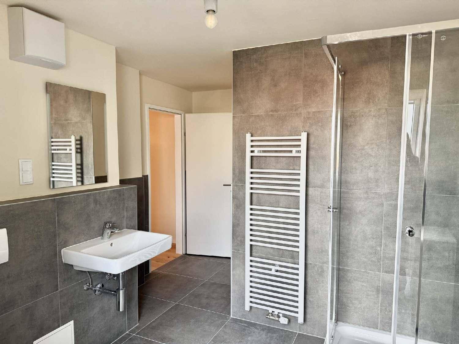 Modernes Badezimmer mit grauen Fliesen, Duschkabine und beheiztem Handtuchhalter.