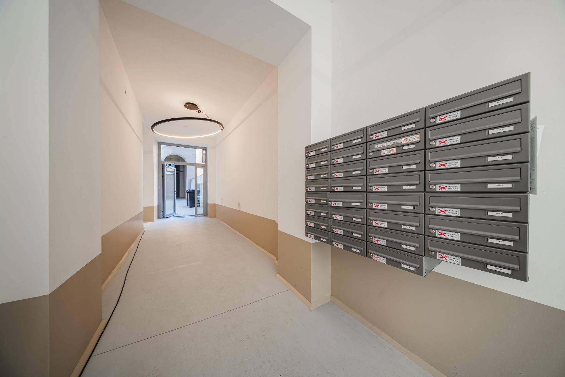 Heller Eingangsbereich eines Mehrfamilienhauses mit modernen Briefkästen und schlichtem Design.