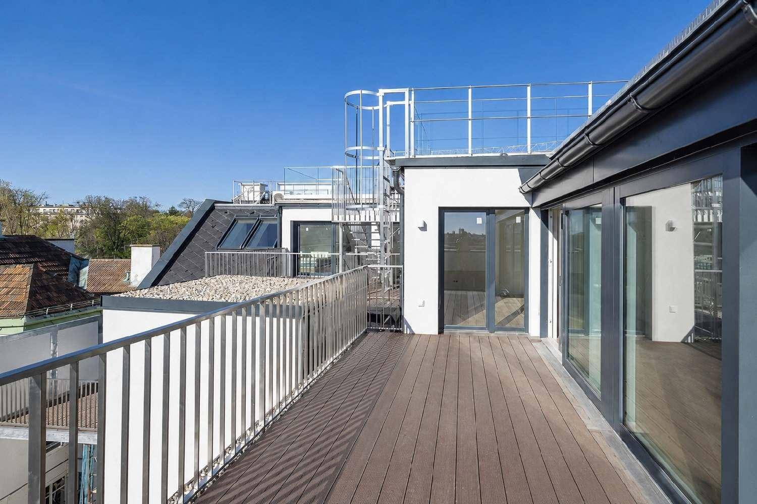 Geräumige Dachterrasse mit Holzbelag und Metallgeländer, ideal für Entspannung im Freien.